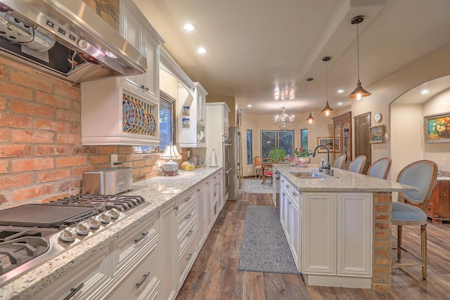 kitchen featuring sink, a breakfast bar area, a kitchen island with sink, white cabinets, and exhaust hood