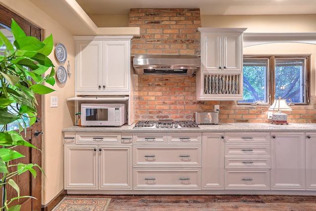 kitchen featuring light stone counters, white cabinets, exhaust hood, and stainless steel gas cooktop