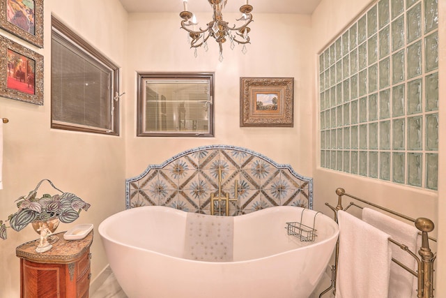 bathroom featuring a washtub and a notable chandelier