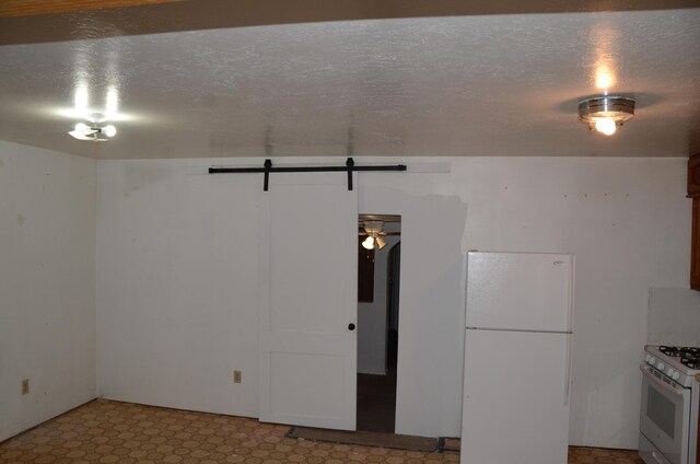 below grade area featuring a textured ceiling, light floors, and freestanding refrigerator