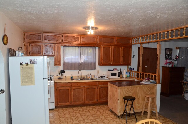 kitchen with brown cabinets, light floors, a breakfast bar area, a sink, and white appliances