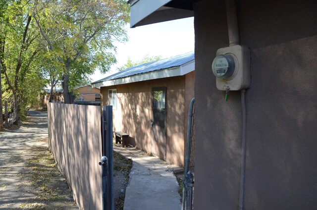 view of property exterior with fence, metal roof, and stucco siding