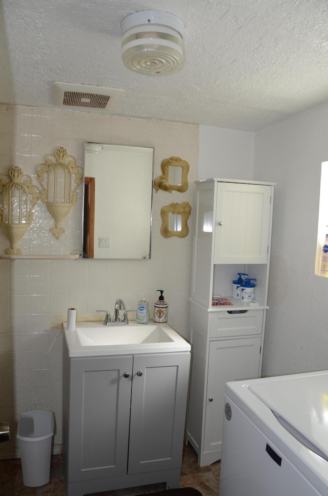 bathroom featuring visible vents, washer / clothes dryer, a textured ceiling, and vanity