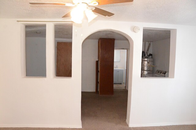 hall with carpet floors, arched walkways, and a textured ceiling