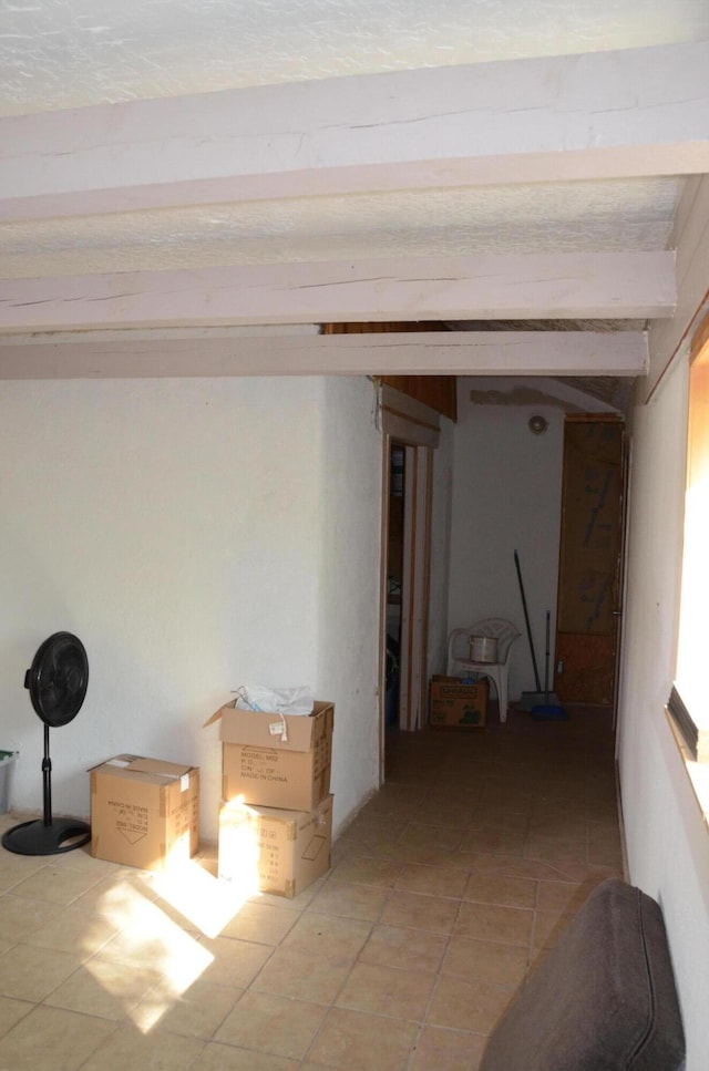 hallway with light tile patterned floors and beam ceiling