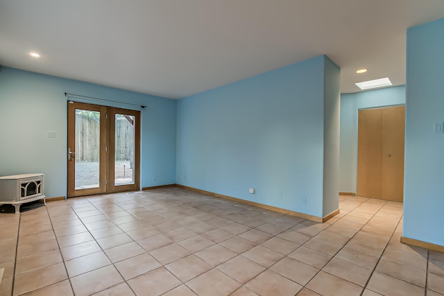 tiled spare room featuring french doors and a skylight