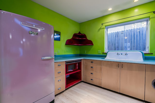 kitchen featuring stainless steel fridge, sink, and light wood-type flooring