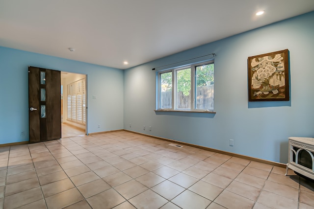 tiled spare room featuring a wood stove