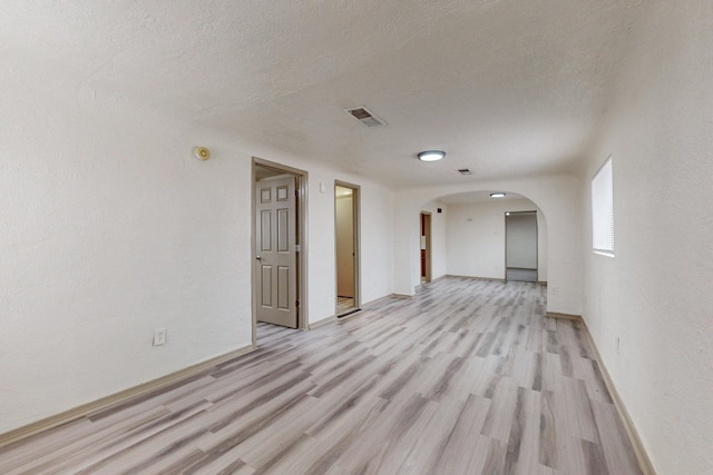 unfurnished room featuring a textured ceiling and light hardwood / wood-style floors