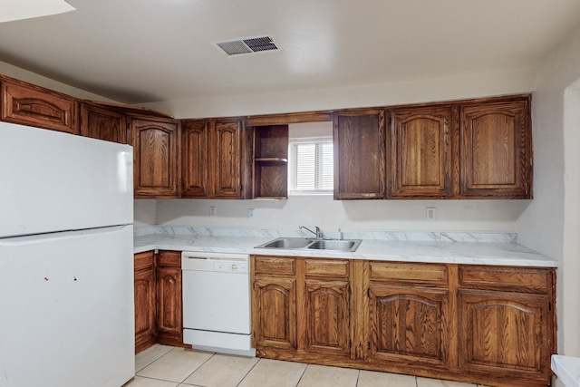 kitchen featuring sink, light tile patterned floors, and white appliances