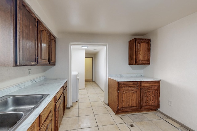 kitchen with washer / clothes dryer, sink, and light tile patterned floors