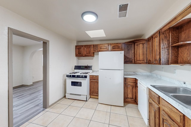 kitchen featuring light tile patterned flooring, white appliances, and sink