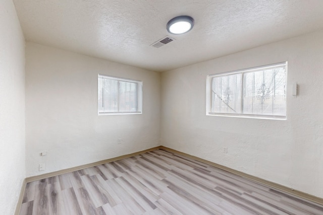 unfurnished room featuring a textured ceiling and light hardwood / wood-style flooring