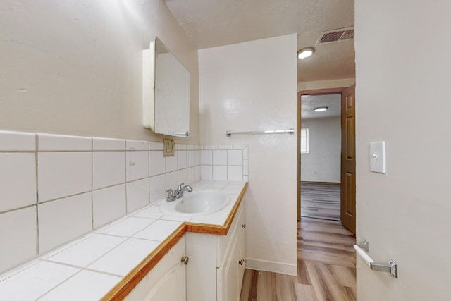 bathroom with hardwood / wood-style floors, vanity, and a textured ceiling