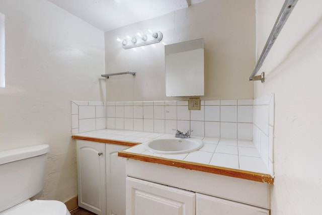 bathroom featuring vanity, toilet, and tasteful backsplash