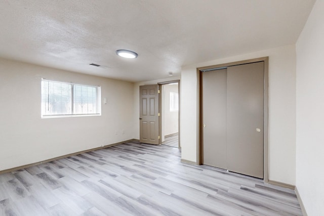 unfurnished bedroom with a closet, a textured ceiling, and light wood-type flooring