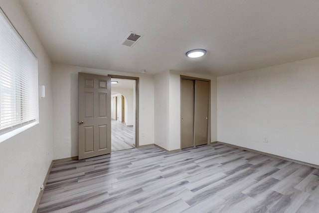 unfurnished bedroom with a closet and light wood-type flooring