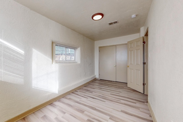 unfurnished bedroom with a closet and light hardwood / wood-style flooring