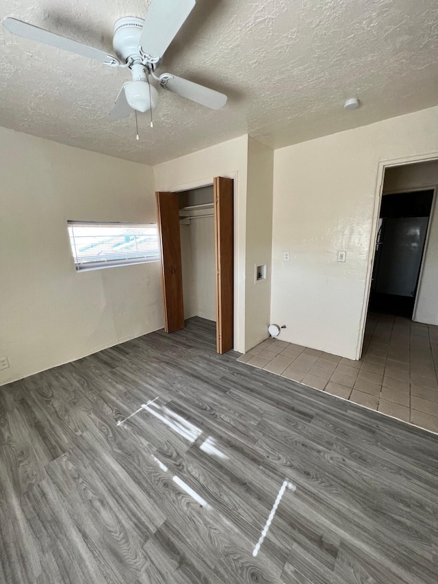 unfurnished bedroom featuring ceiling fan, wood-type flooring, a textured ceiling, and a closet