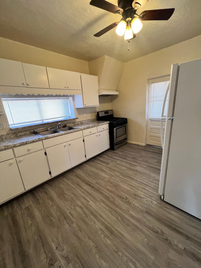 kitchen with white cabinets, gas stove, sink, and white refrigerator