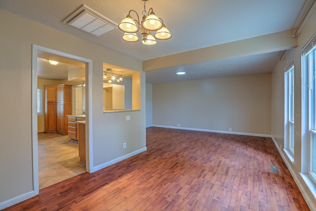 empty room featuring light wood-type flooring and a chandelier