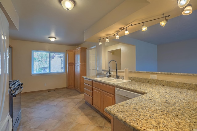 kitchen with light tile patterned floors, white dishwasher, light stone counters, sink, and black gas stove