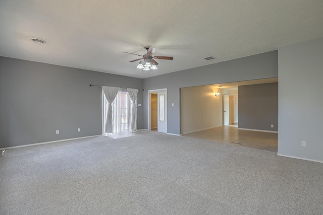 spare room featuring light colored carpet, ceiling fan, and a textured ceiling