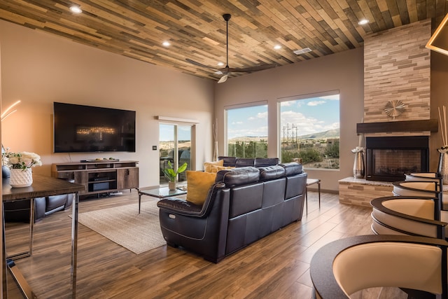 living room with a towering ceiling, wood ceiling, hardwood / wood-style flooring, and a fireplace