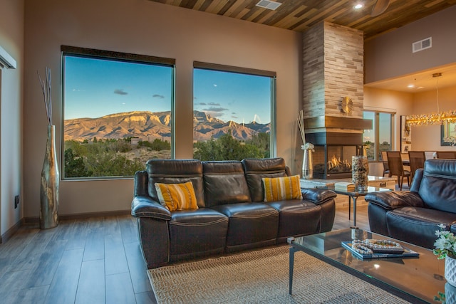 interior space featuring a high ceiling, a stone fireplace, a mountain view, wood-type flooring, and wooden ceiling