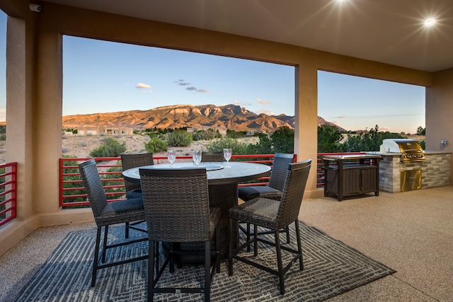 patio terrace at dusk featuring area for grilling, a mountain view, and grilling area