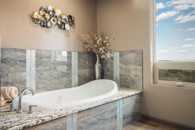 bathroom featuring hardwood / wood-style floors and a relaxing tiled tub