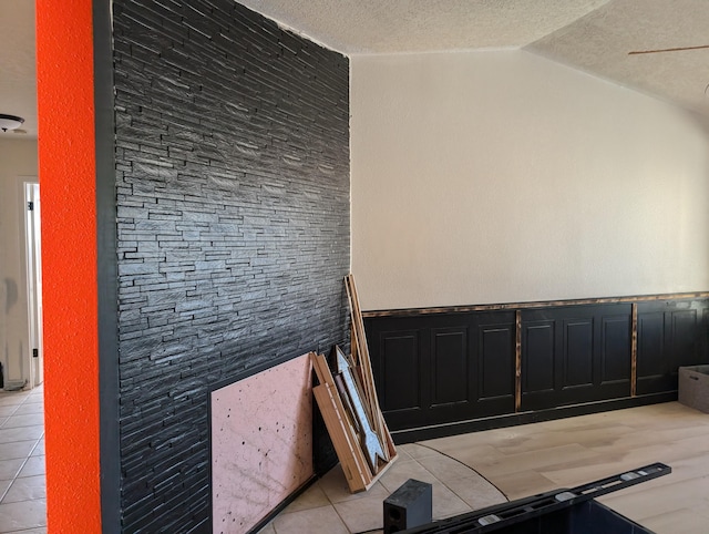 interior space with lofted ceiling, a textured ceiling, and tile patterned floors