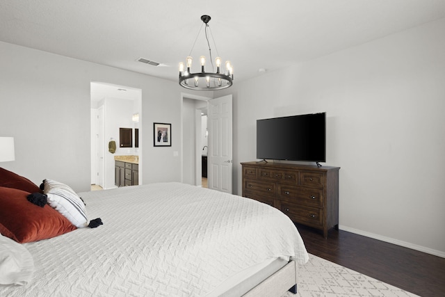 bedroom with dark hardwood / wood-style floors, a chandelier, and connected bathroom