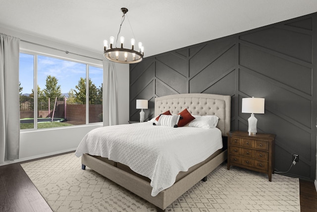 bedroom with an inviting chandelier and light wood-type flooring