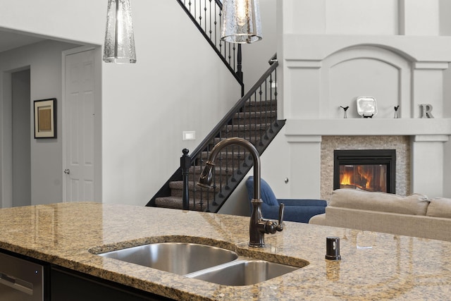 kitchen with stainless steel dishwasher, sink, and light stone countertops