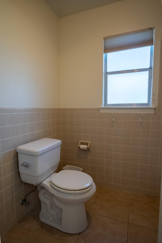 bathroom featuring tile patterned flooring, toilet, and tile walls