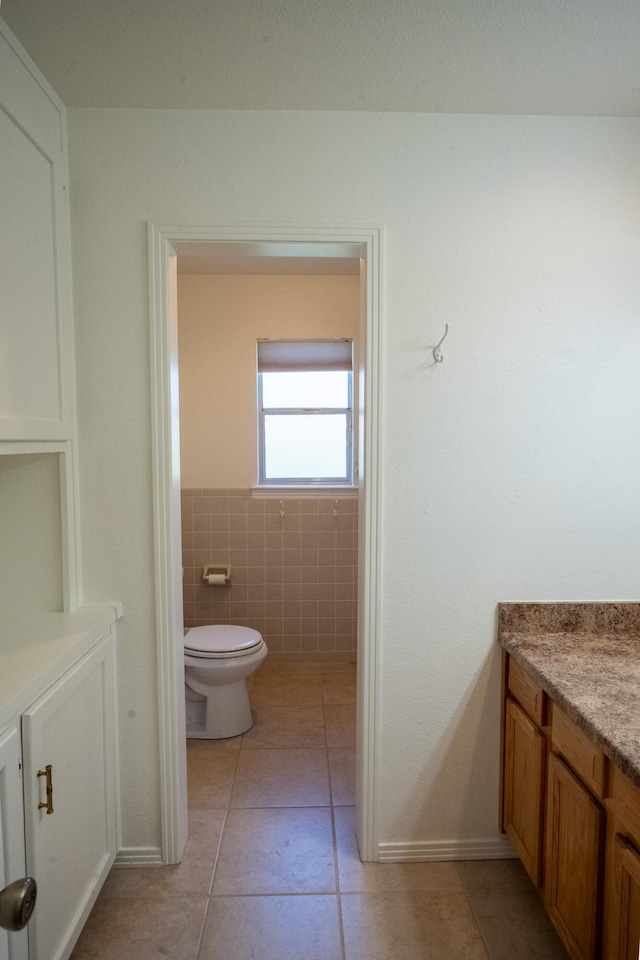 bathroom featuring tile patterned floors, vanity, toilet, and tile walls