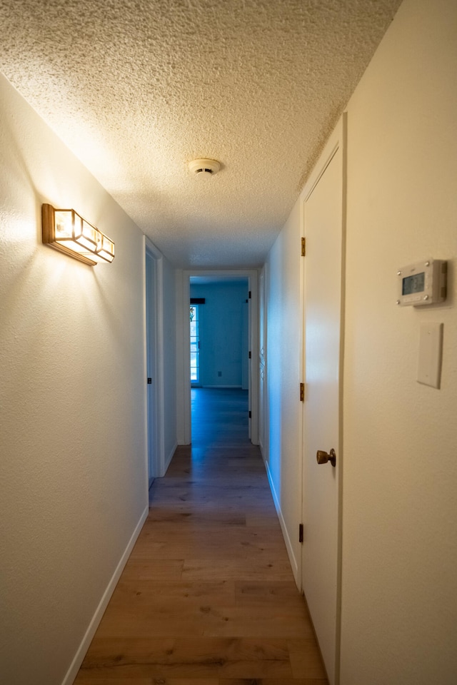 hallway featuring wood-type flooring and a textured ceiling