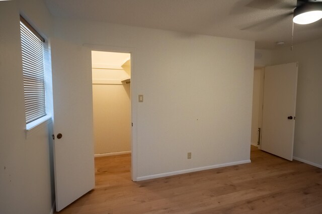 unfurnished bedroom with ceiling fan, light hardwood / wood-style floors, a spacious closet, and a closet