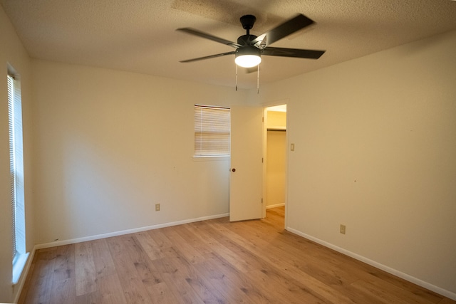 spare room with a wealth of natural light, a textured ceiling, light hardwood / wood-style floors, and ceiling fan