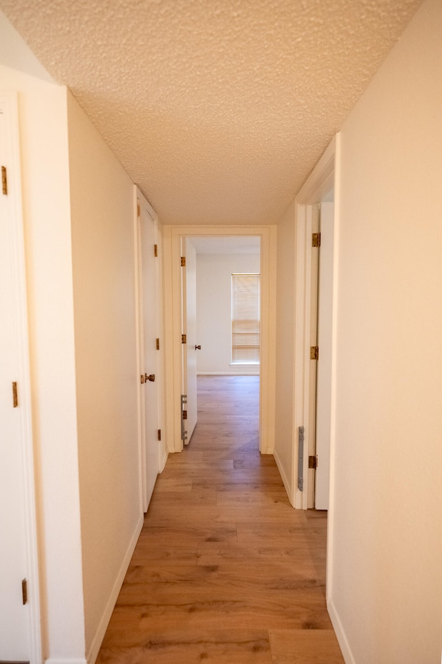 corridor featuring light hardwood / wood-style floors and a textured ceiling