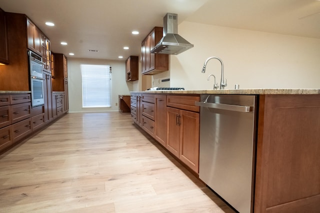 kitchen featuring sink, light wood-type flooring, wall chimney range hood, and stainless steel appliances