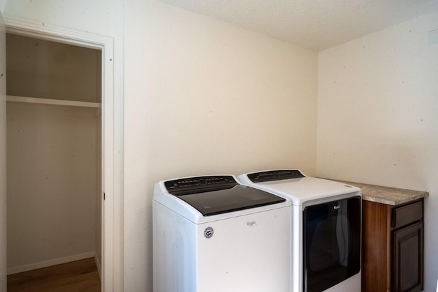 laundry area with a textured ceiling, hardwood / wood-style flooring, and washer and clothes dryer