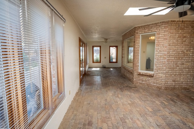 hall with a textured ceiling, brick wall, and a skylight