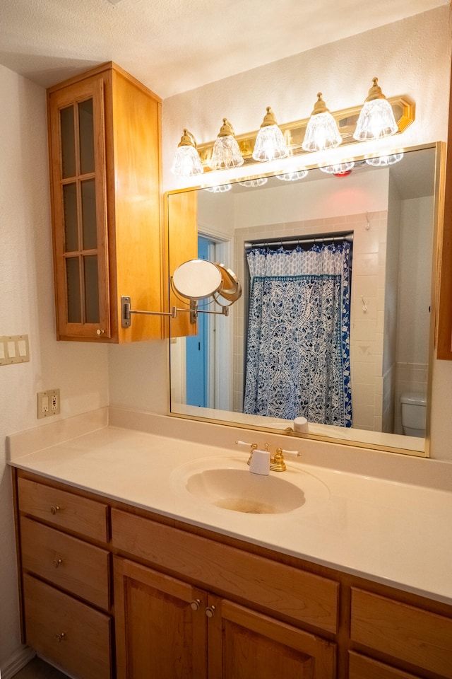 bathroom featuring a shower with curtain, vanity, toilet, and a textured ceiling