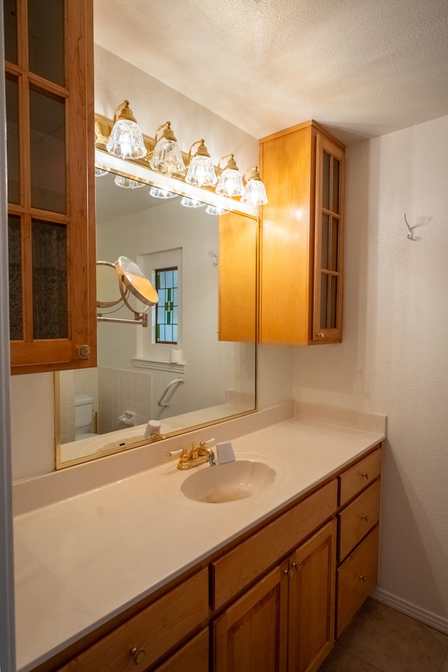 bathroom featuring tile patterned floors, vanity, toilet, and a textured ceiling