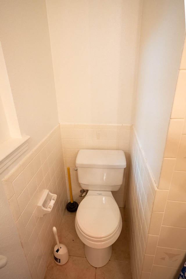 bathroom with tile patterned floors, tile walls, and toilet