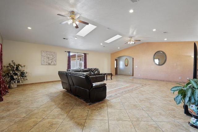 living room with lofted ceiling with skylight, baseboards, arched walkways, and ceiling fan