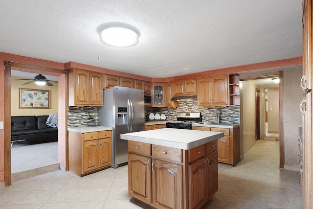 kitchen featuring light tile patterned floors, decorative backsplash, stainless steel appliances, and a center island