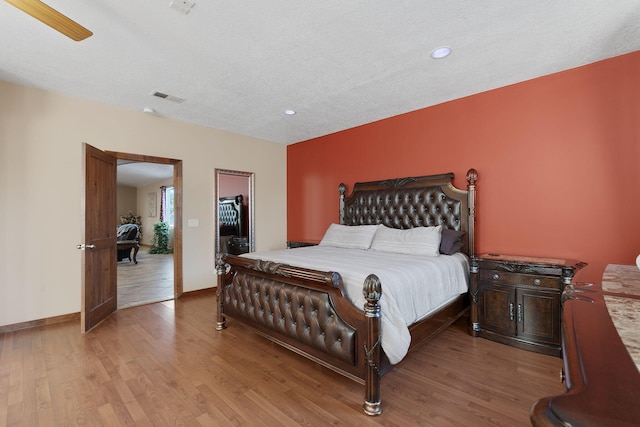bedroom with visible vents, a textured ceiling, light wood-type flooring, and baseboards